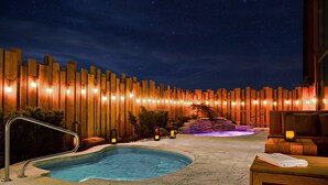 A nighttime pool area with a wooden fence, a hot tub, and a massage table. - Marriott Niagara Falls Fallsview Hotel & Spa (Niagara Falls)