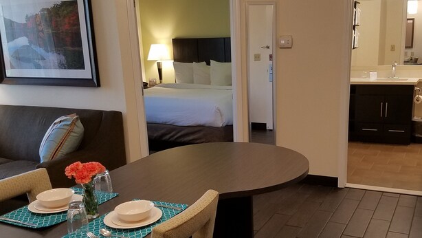 A hotel room with a dining area, a bed, and a bathroom visible through an open door.