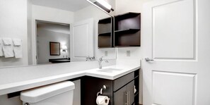 Un baño moderno con un lavamanos blanco, armarios oscuros y un espejo sobre el lavamanos.
