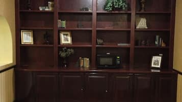 A dark wood-built bookshelf with various decorative items and a microwave.