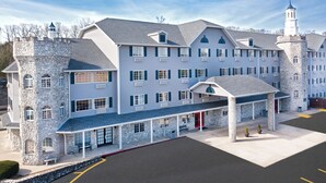 A large, multi-story hotel with a stone tower and a covered entrance area.