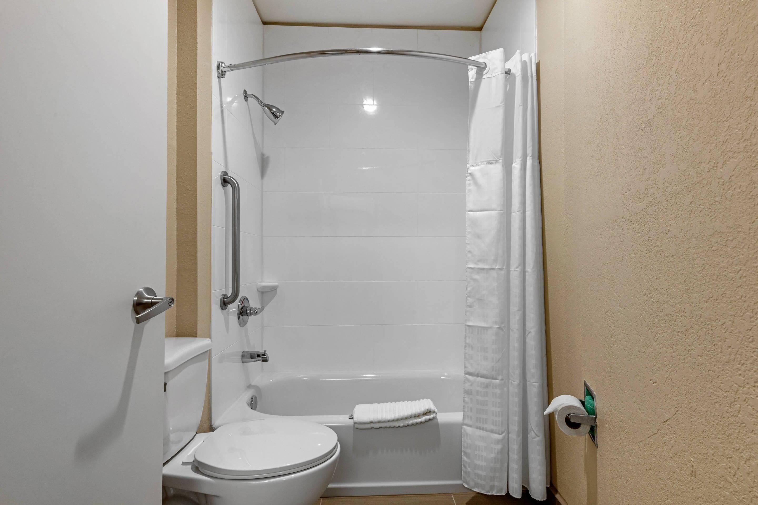 A bathroom with a white toilet, a shower with a curved glass door, and a towel hanging on the wall.