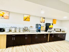 Distribución tipo bufé con varios dispensadores de comida y una barra.