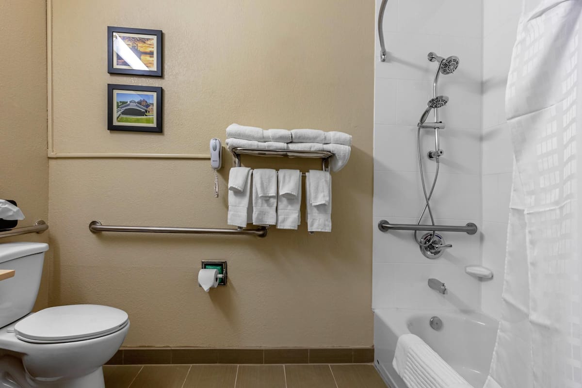 A bathroom with a toilet, a shower, and a towel rack with folded towels.