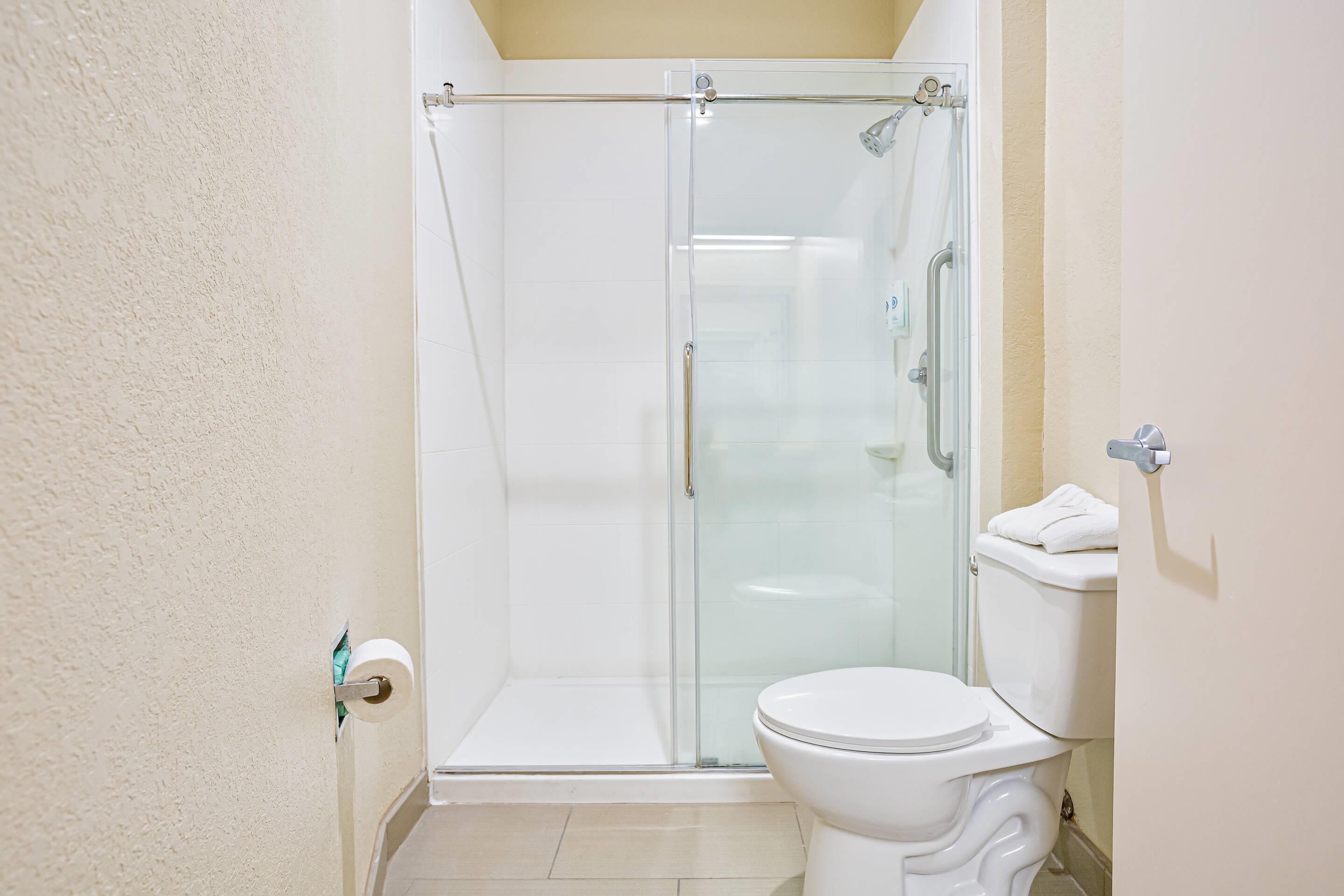 Une salle de bain avec une douche à parois de verre, des toilettes blanches et un porte-serviettes.