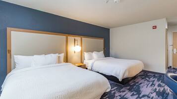 Camera d'albergo con due letti, un comodino, una lampada a parete e un bagno con un lavandino blu.