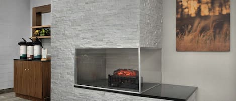 Een modern interieur met een open haard met steenstructuur, een houten kast en een lijstwerk kunstwerk aan de muur.