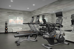 Ein Fitnessstudio mit Laufbändern, Kraftgeräten und einer Spiegelwand.