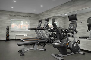 A gym with treadmills, weight machines, and a mirrored wall.