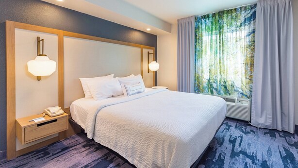Une chambre d’hôtel avec un grand lit, des lampes de chevet, une table de nuit et une fenêtre avec des rideaux.