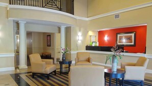 A lobby with a reception desk, two sofas, a coffee table, and a striped carpet.