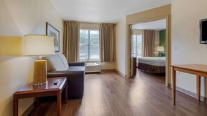 A hotel room with a sofa, a small table with a lamp, a bed, and a TV.