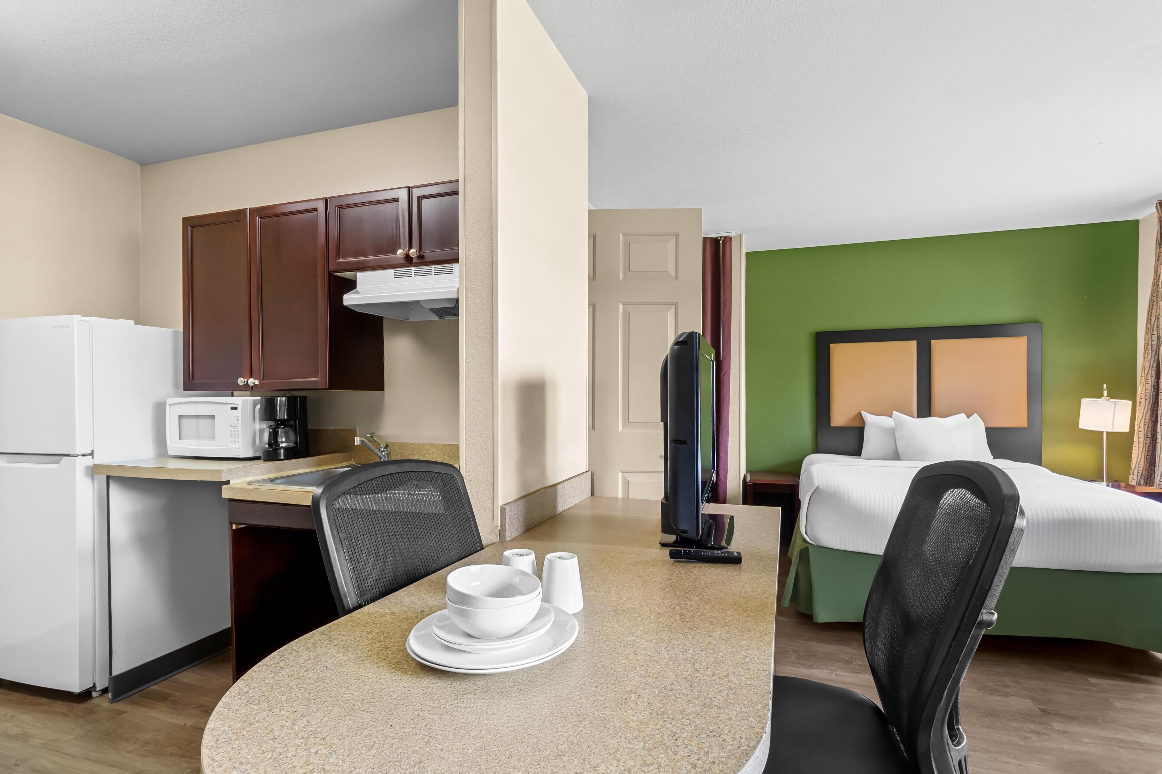 Une chambre d’hôtel compacte comprenant un coin cuisine, un espace repas et un lit.