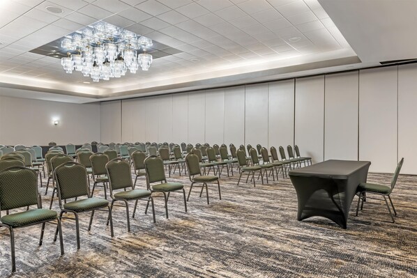 A conference room with rows of green chairs, a black table, and a chandelier. - Best Western Plus Eau Claire Conference Center (Eau Claire)