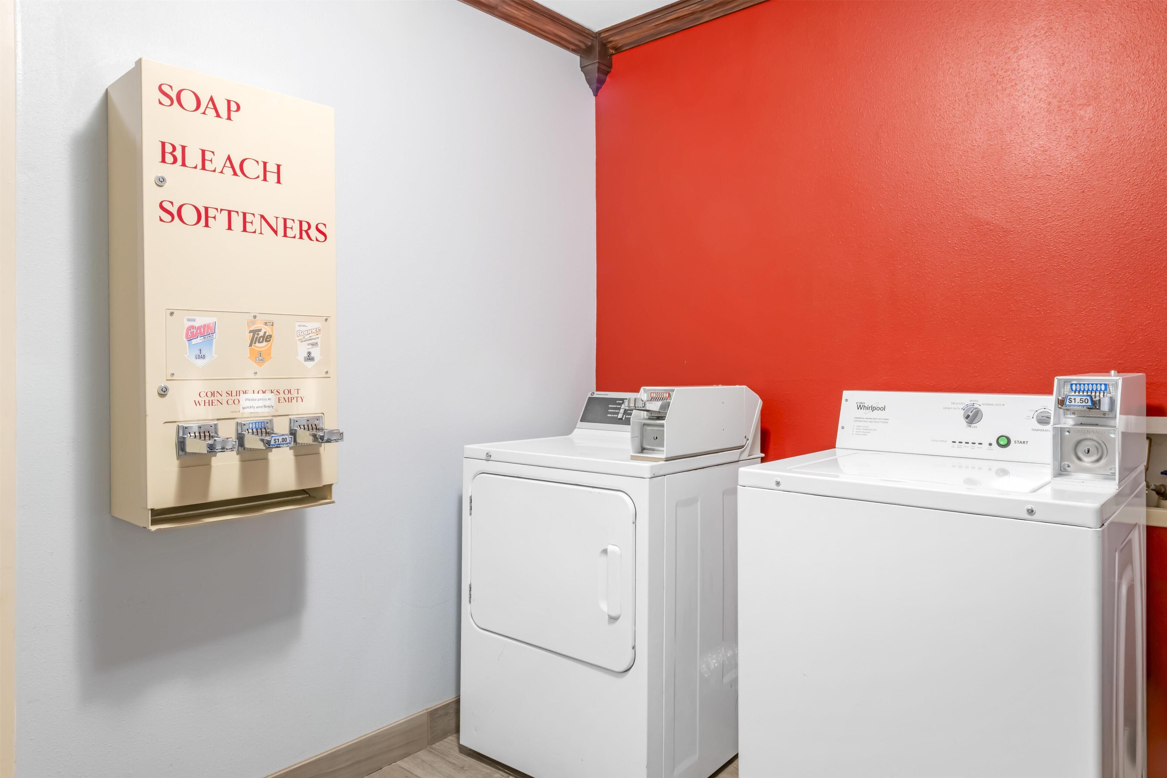 A laundry room with two washers and a coin-operated soap, bleach, and softener dispenser.