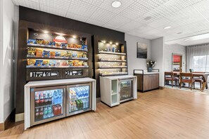 A snack bar with shelves of snacks and a refrigerator with beverages. - Hampton Inn Florence Midtown near University of North Alabama (Florence)