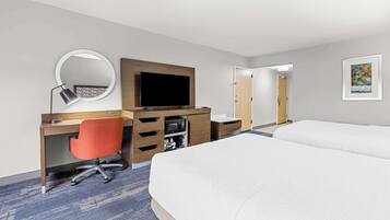 Ein Hotelzimmer mit Bett, Schreibtisch mit Stuhl, Fernseher, Spiegel und Mikrowelle.