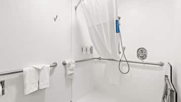 Un baño blanco con ducha, barras de apoyo y un perchero.