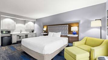 Une chambre d’hôtel comprenant un lit, un bureau avec un micro-ondes, un lavabo, une chaise et une table de chevet avec une lampe.
