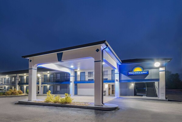 A Days Inn & Suites with a covered parking area, multiple floors, and a visible staircase leading to the entrance. - Days Inn by Wyndham Hamilton (Hamilton)