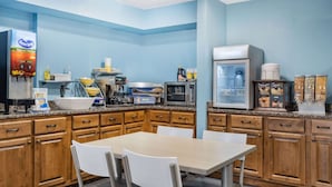 A kitchen with wooden cabinets, a microwave, a refrigerator, and a coffee machine. - Days Inn by Wyndham Hamilton (Hamilton)