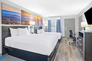A hotel room with a large bed, two bedside tables with lamps, a desk with a chair, a television, and a window with curtains. - Days Inn by Wyndham Hamilton (Hamilton)