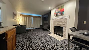 A modern living room with a fireplace, a dining area with a table and chairs, and a seating area with sofas and a coffee table.