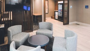 A hotel lobby with seating arrangements, a television, and a refrigerator. - Holiday Inn Express Lompoc by IHG (Lompoc)