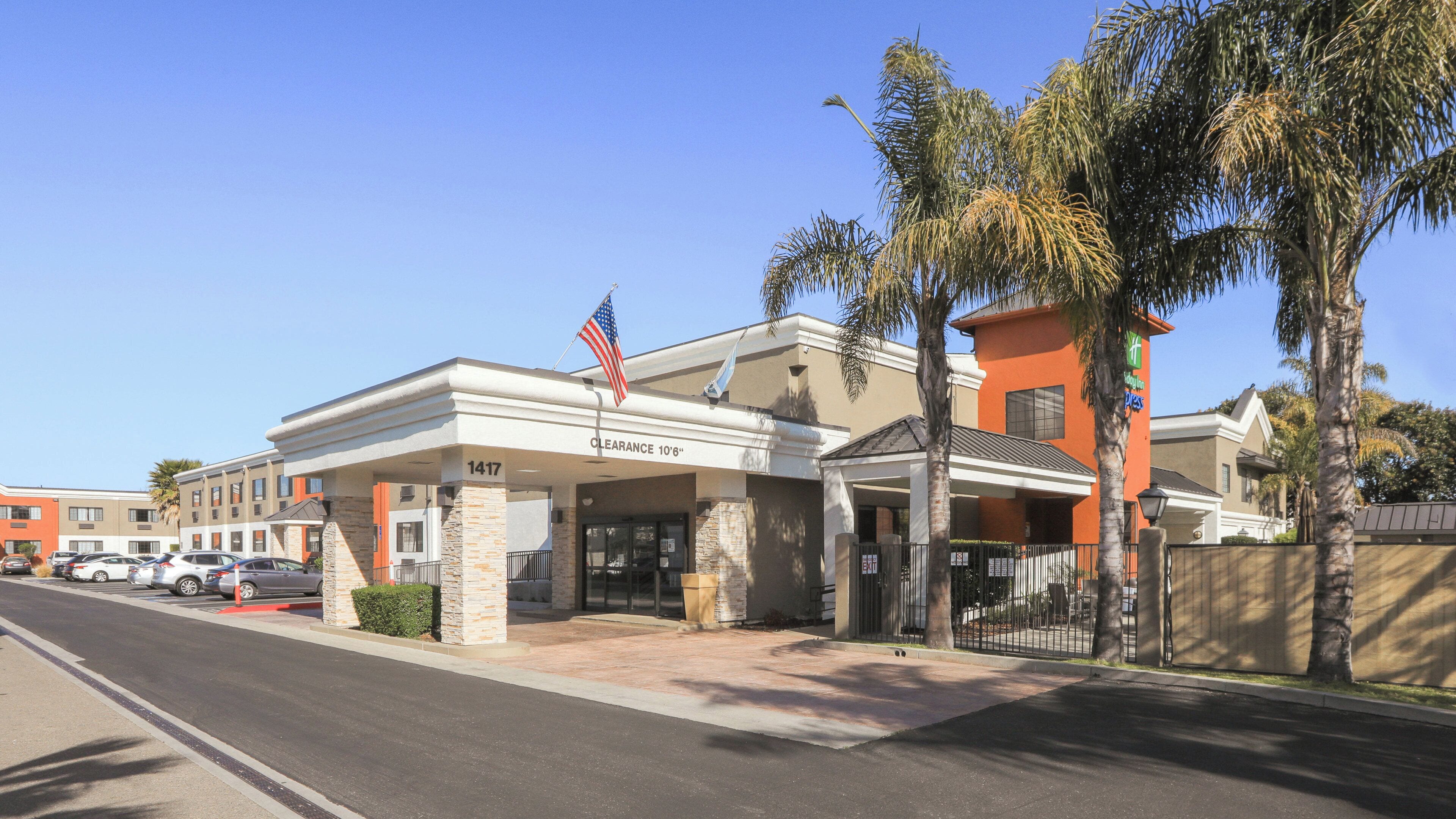 A hotel with a clear entrance, a parking lot, and a flag.
