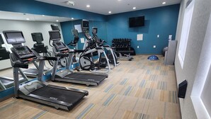 A gym with treadmills, elliptical machines, and a weight bench.