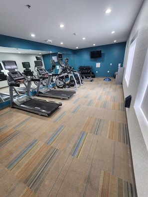 A gym with treadmills, elliptical machines, and a weight bench.