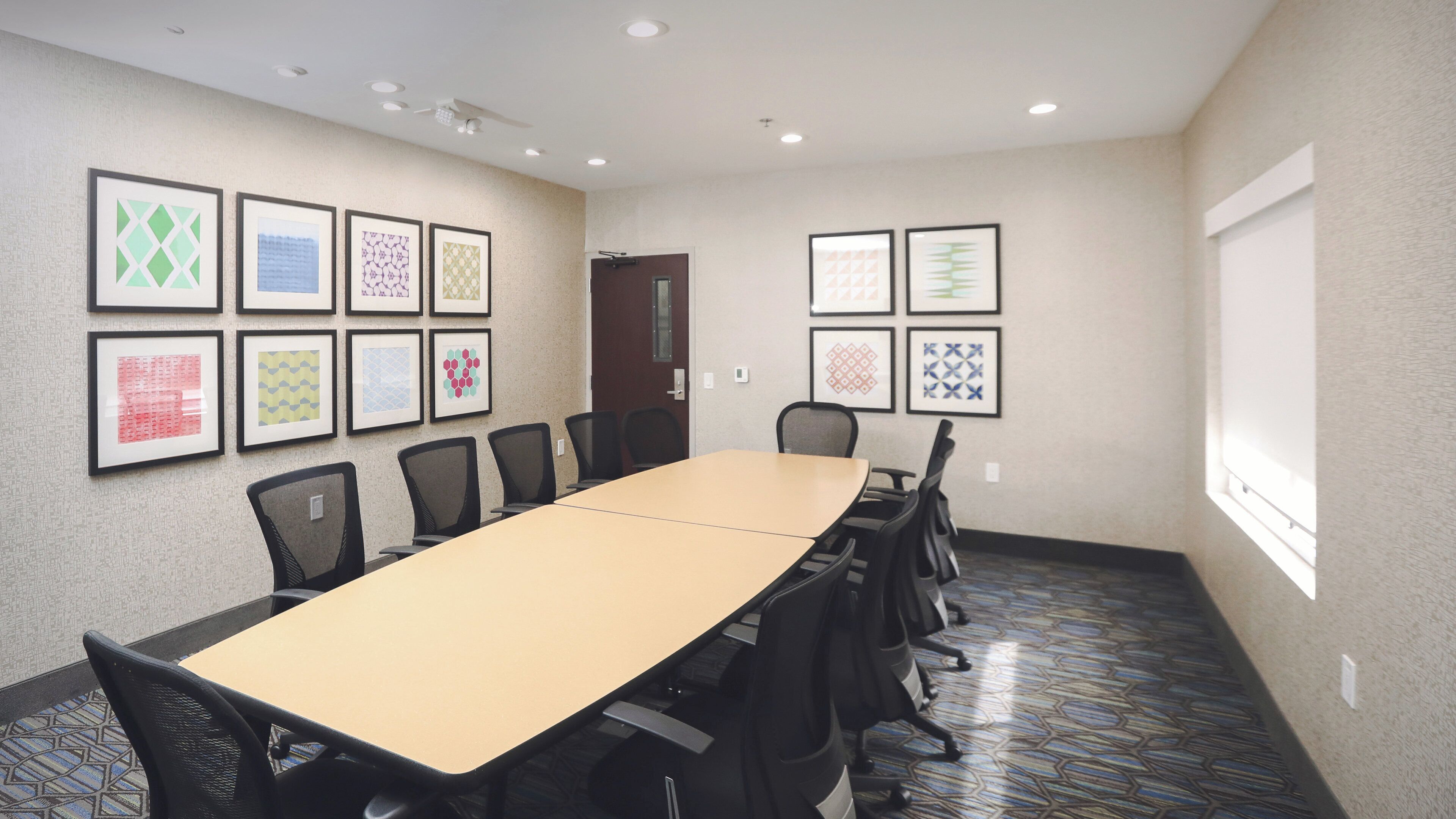 A conference room with a long table, chairs, and framed artwork on the walls.