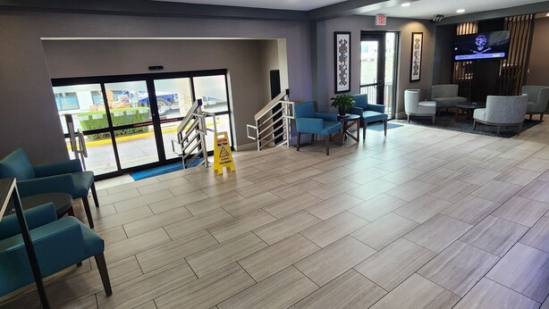 A spacious lobby with a tiled floor, seating area, and a television screen.