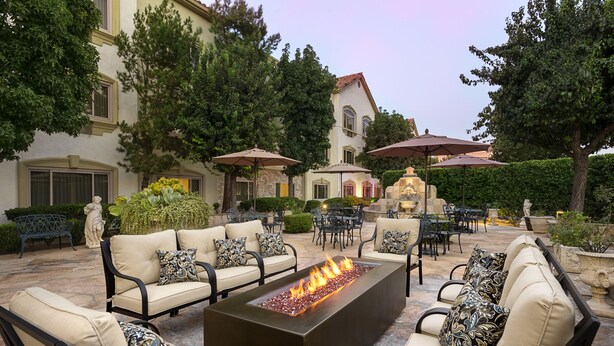 An outdoor patio with a fire feature, seating, and umbrellas. - Ayres Suites Ontario at the Mills Mall - Rancho Cucamonga (Ontario)