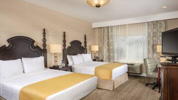 A hotel room with two beds, a television, a desk, and a chair.