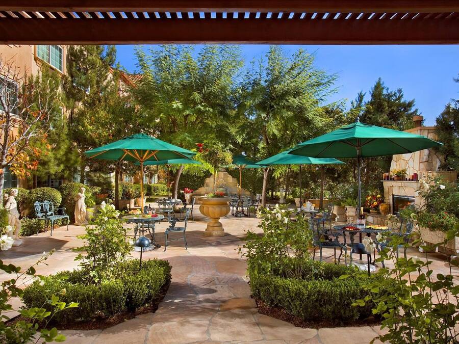 An outdoor patio area with stone flooring, green umbrellas, and outdoor seating.