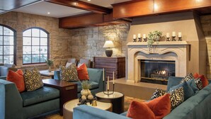 A cozy living room with a stone wall, fireplace, and comfortable seating. - Ayres Suites Ontario at the Mills Mall - Rancho Cucamonga (Ontario)