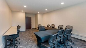 A conference room with a large table and multiple chairs, carpeted floor, and recessed ceiling lights. - Extended Hotel Studio (San Dimas)
