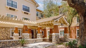 A building with a covered patio area, stone pillars, and a sign labeled "Lobby". - Extended Hotel Studio (San Dimas)