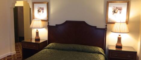 A hotel room with a large bed, two bedside tables with lamps, and framed pictures on the walls.