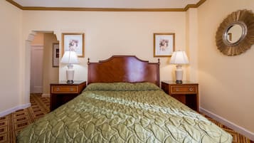 Une chambre d’hôtel avec un grand lit, deux tables de chevet avec des lampes, une tête de lit en bois et deux tableaux encadrés accrochés aux murs.