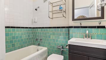 Une salle de bain avec une baignoire, des toilettes et un meuble-lavabo avec un miroir.