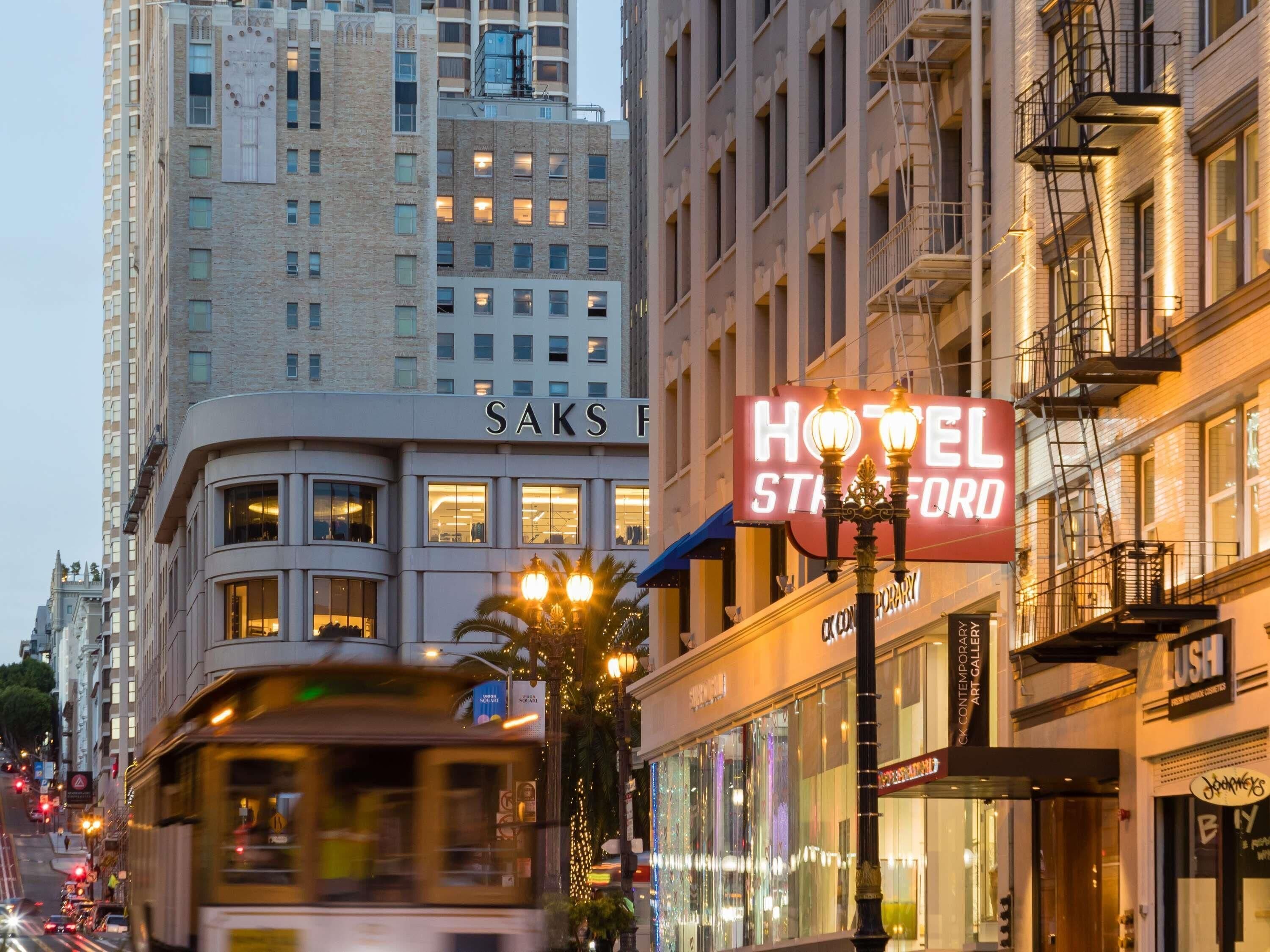 A hotel with a prominent sign, a street view with a tram, and surrounding buildings.