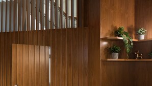 Un interior moderno con un sofá azul, paneles de madera y una escalera.