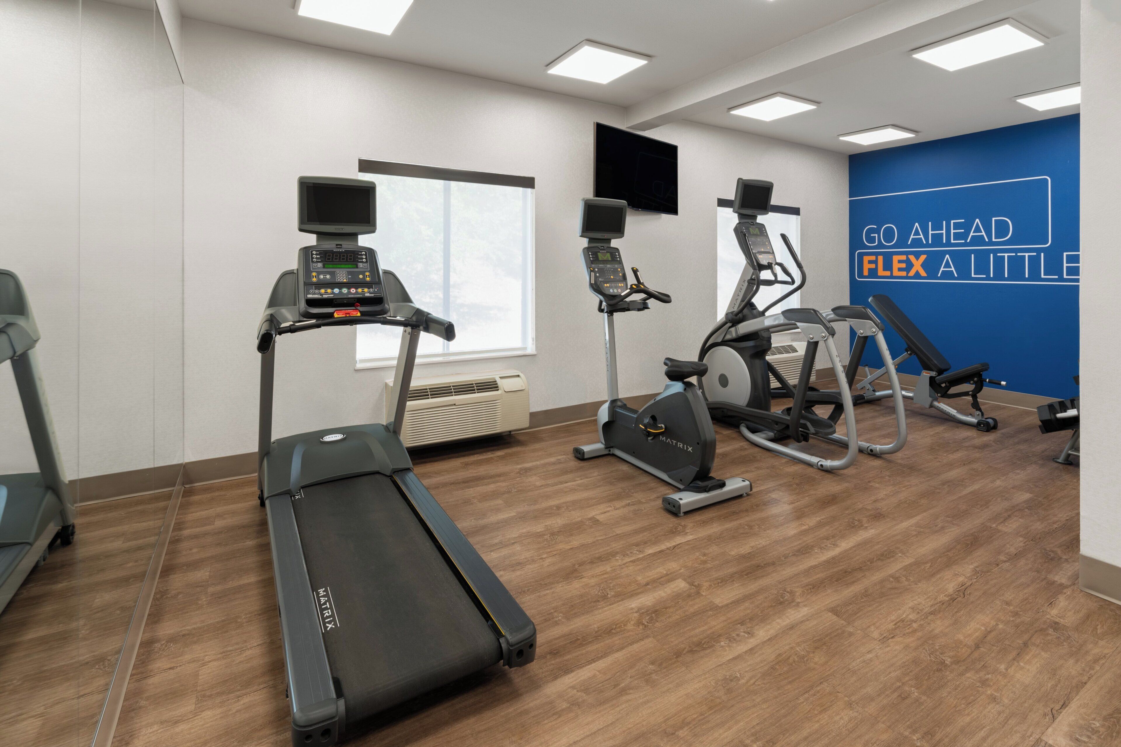 A gym with treadmills, an elliptical, and a wall with motivational text.