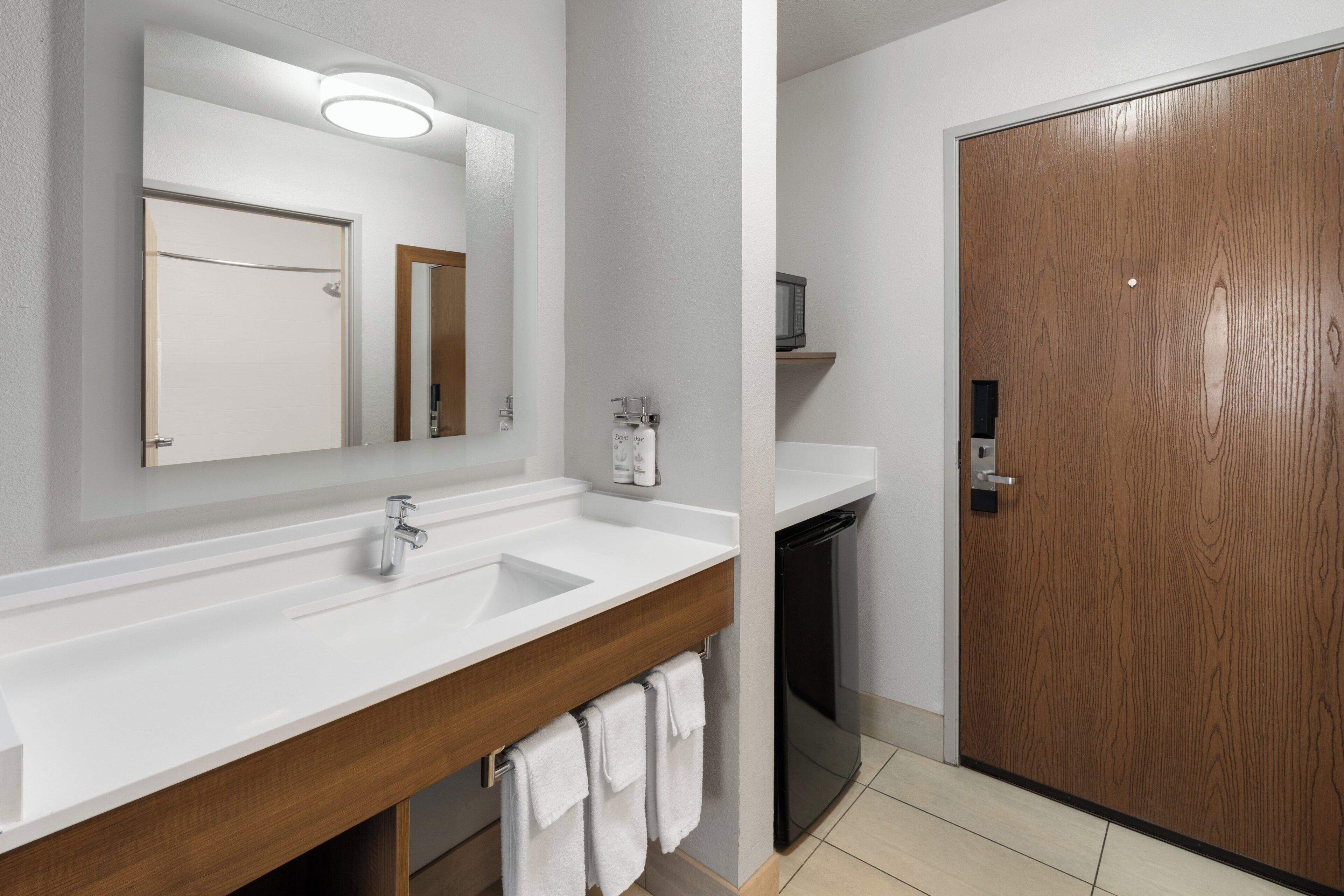 A bathroom with a white sink, a mirror, a wooden vanity, and a towel rack.