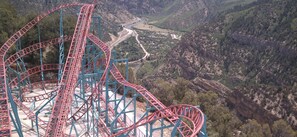 A roller coaster with multiple loops and turns, set against a backdrop of a mountainous landscape with a winding road and a small settlement. - Holiday Inn Express Glenwood Springs by IHG (Glenwood Springs)