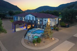 Un hotel Holiday Inn Express con piscina, mobiliario exterior y vistas a las montañas.