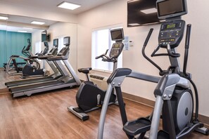 Un gimnasio con cintas de correr, elípticas y bicicletas estáticas.