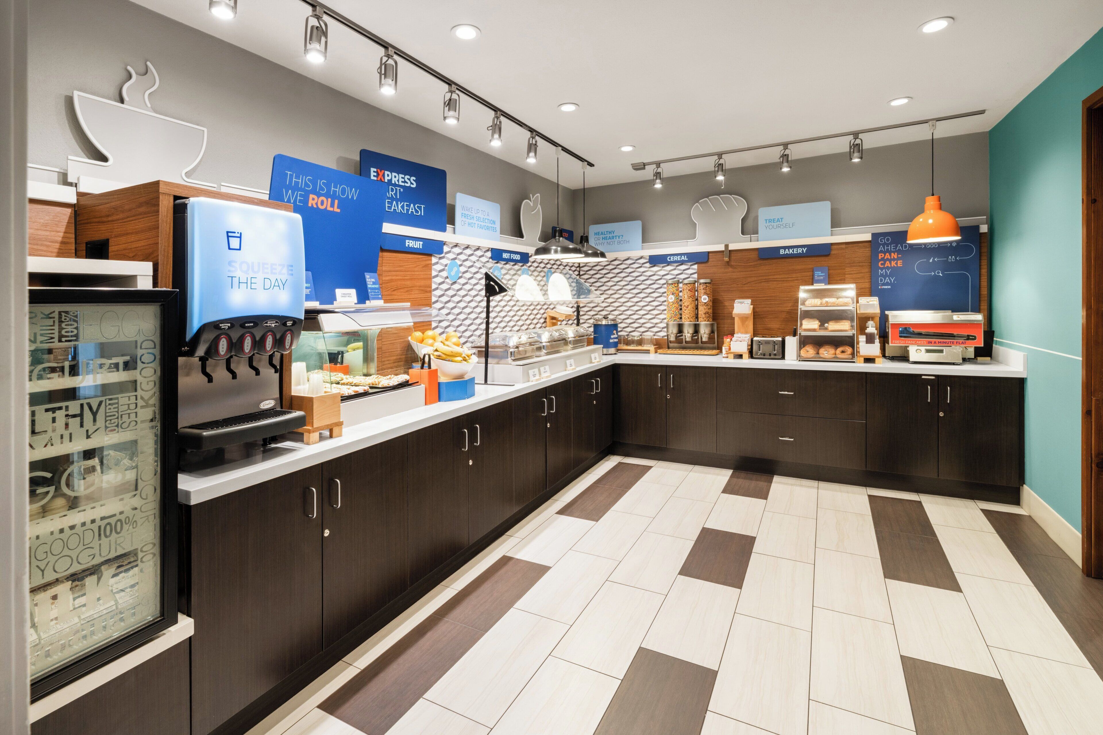 Un moderno comedor con estación de autoservicio, refrigerador y diversas opciones de alimentos.